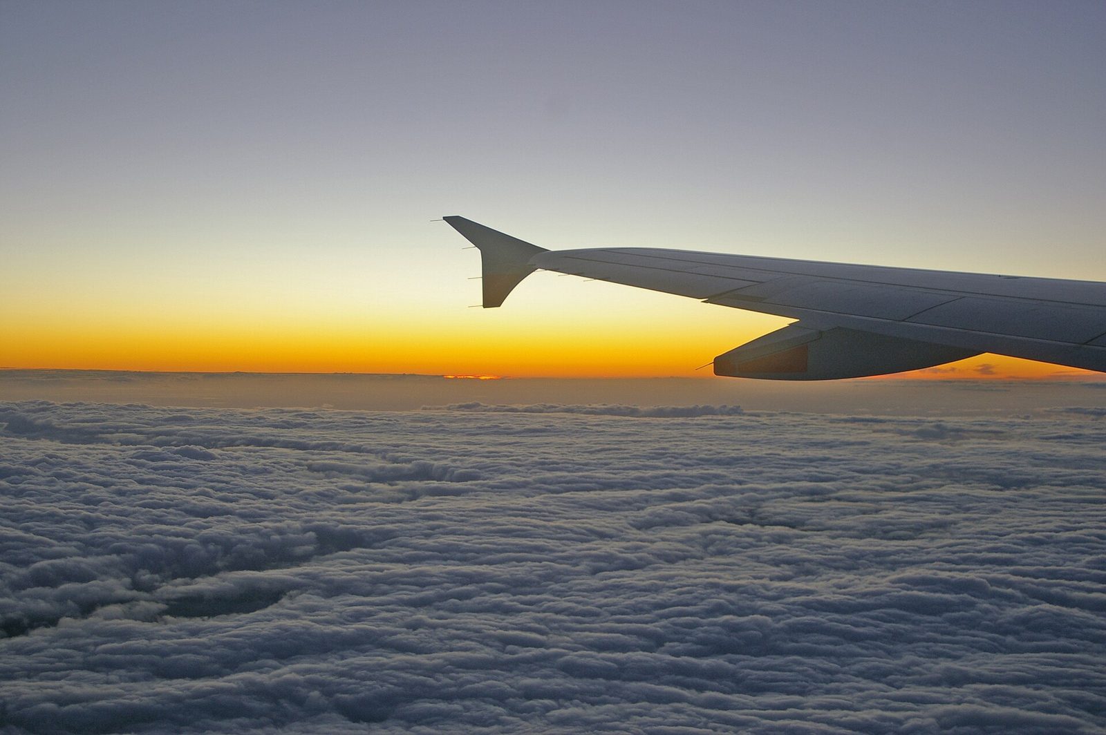 Aircraft wing above the clouds at sunset